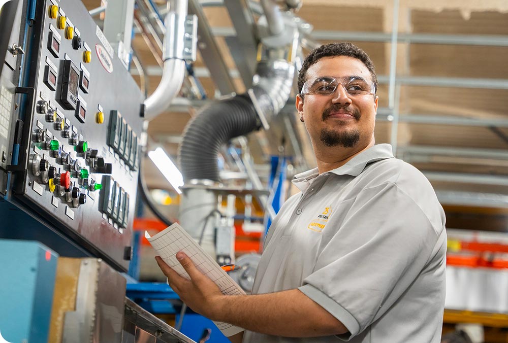 Opérateur souriant devant un panneau de contrôle en usine
