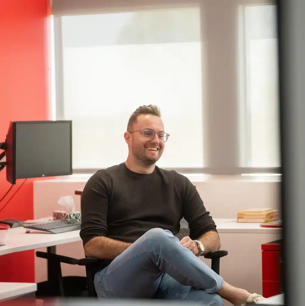 Professionnel souriant, assis dans un bureau lumineux chez Innovair Solutions