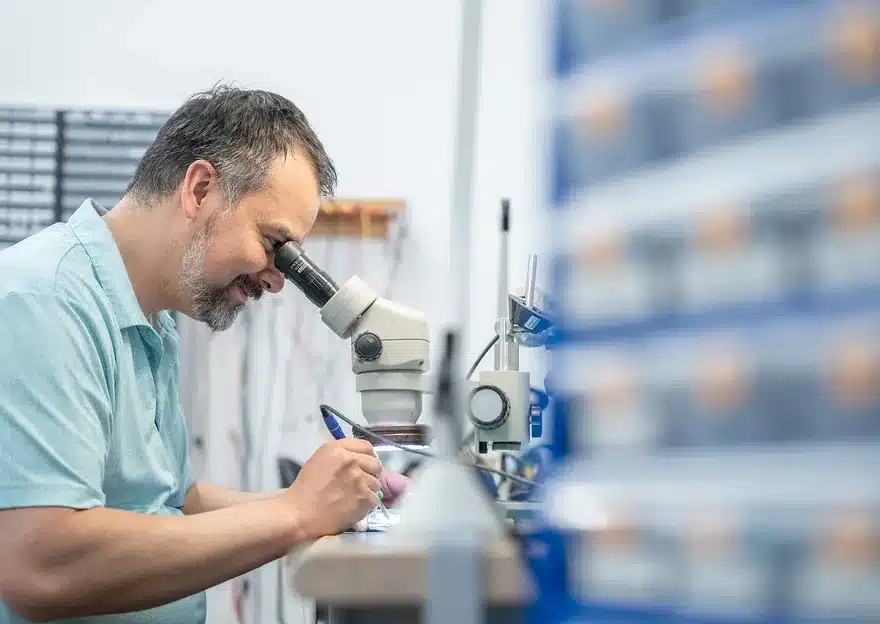 Technicien qui travaille sur un circuit électronique au microscope dans un atelier d’Innovair Solutions