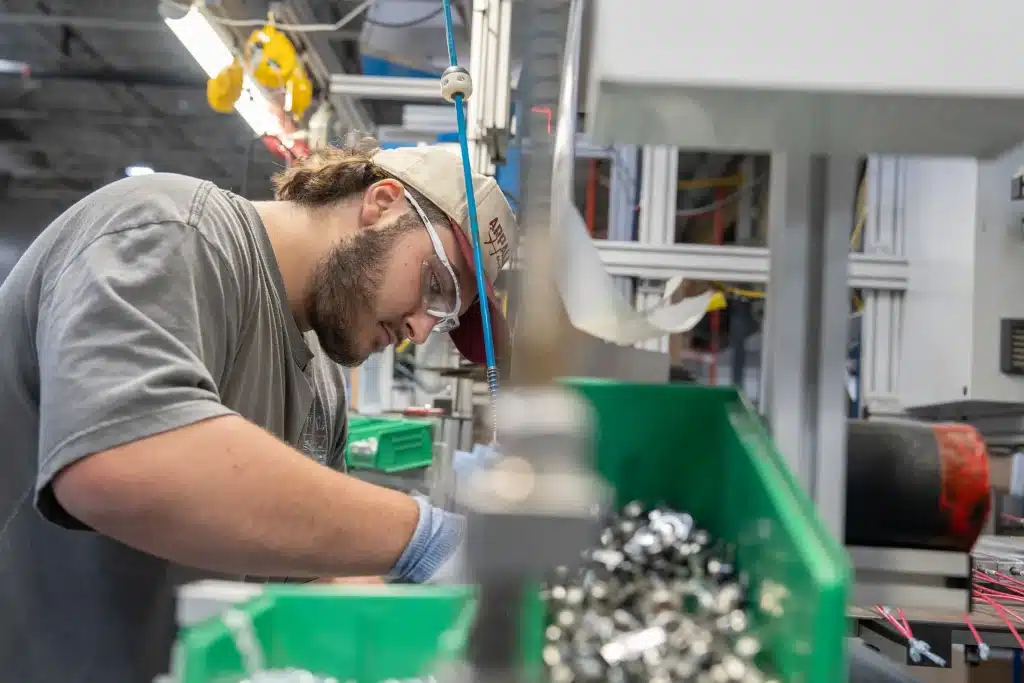 Assembleur avec lunettes de sécurité au travail sur une ligne de production d'Innovair