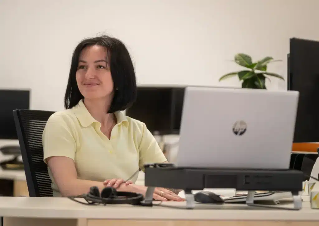 Membre de l’équipe Stelpro souriant à son poste de travail, devant un ordinateur portable